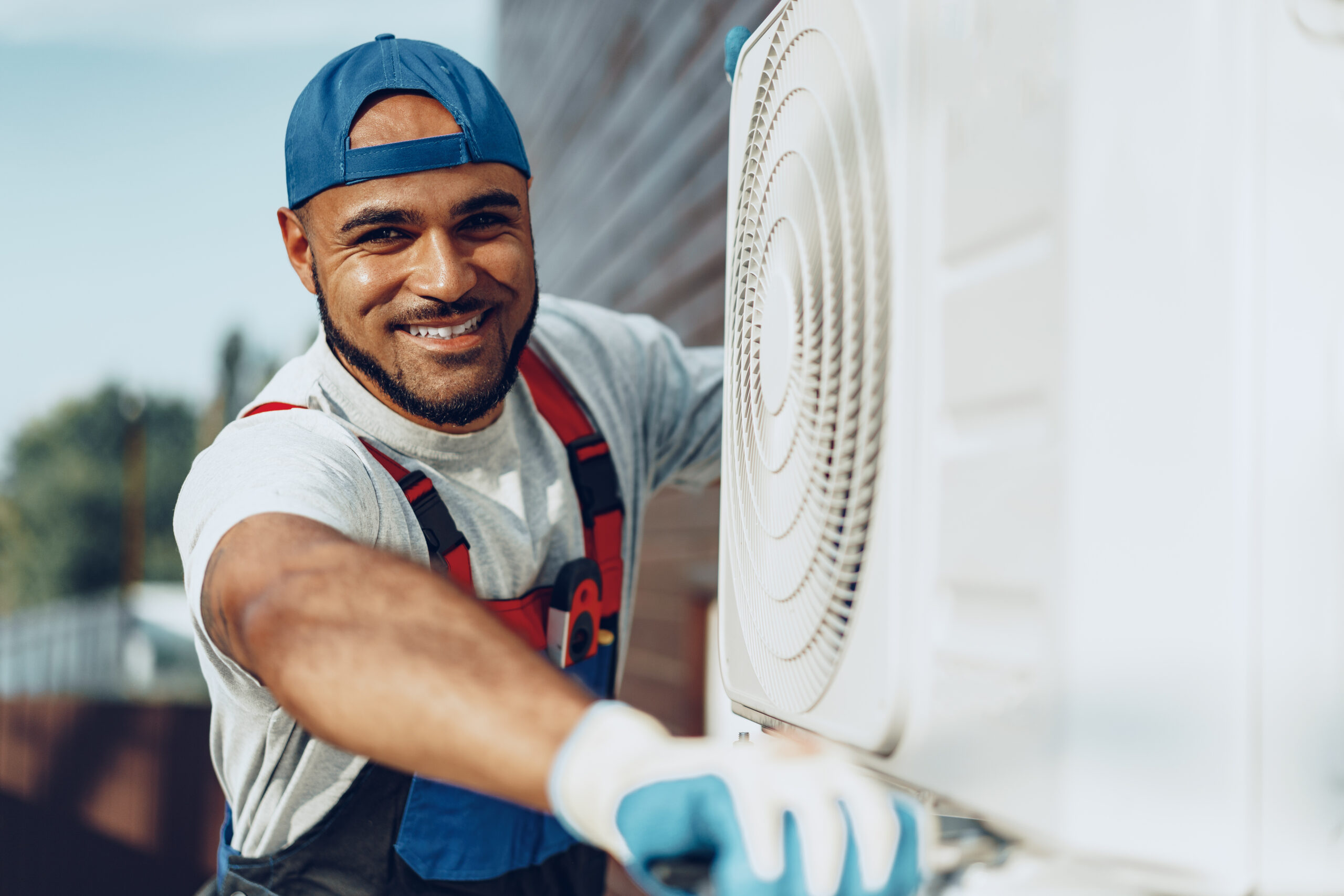 Young black man repairman checking an outside air conditioner unit close up